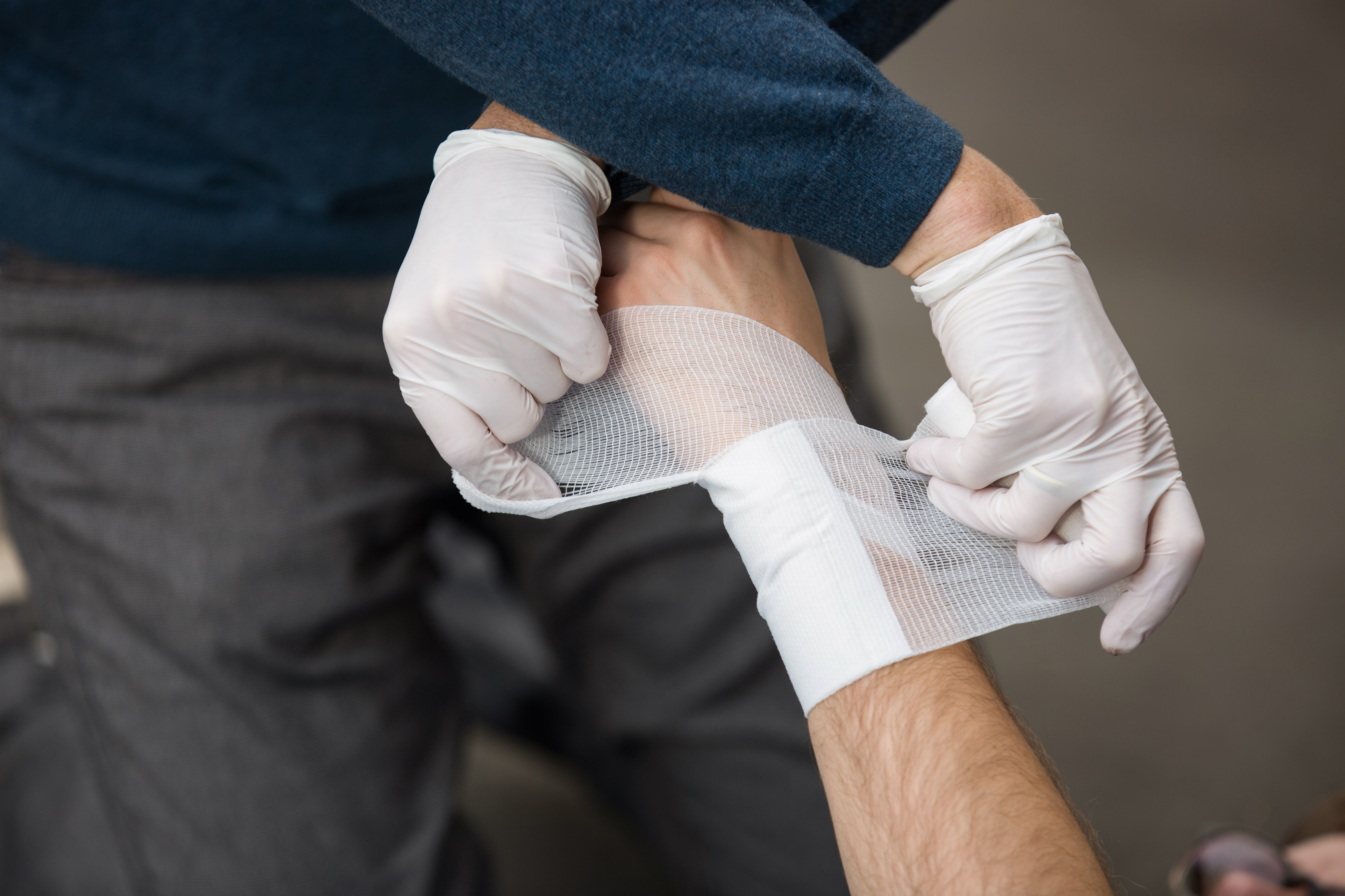 Ein Mann leistet Erste-Hilfe und verbindet eine andere Person.